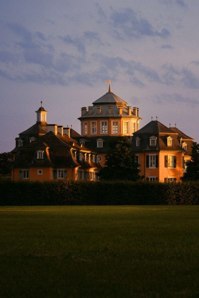 A picturesque view of a historic mansion, Erimitage with a lush green lawn under a twilight sky.