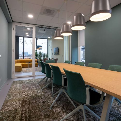 Several chairs put next to a table in a room with a patterned carpet