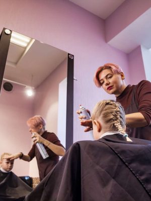Hair salon, Hairdresser makes hairdo for baby in barber shop at mirror.