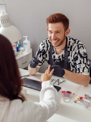 Manicure specialist providing nail service for client in salon